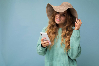 美丽的微笑年轻的金发女郎女人穿蓝色的毛衣他站孤立的蓝色的背景冲浪互联网电话相机