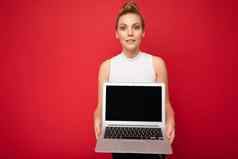 照片美丽的金发碧眼的年轻的女人聚集头发相机持有电脑移动PC空监控屏幕模拟复制空间穿白色t恤孤立的红色的墙背景