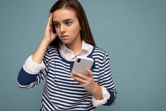 照片深思熟虑的集中有吸引力的年轻的浅黑肤色的女人女孩穿条纹朗斯利耶夫站孤立的蓝色的背景冲浪互联网电话一边思考