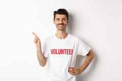 英俊的微笑志愿者t恤指出手指左显示公告站白色背景