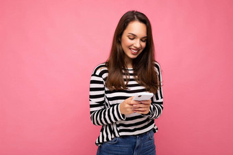 照片漂亮的年轻的微笑浅黑肤色的女人女人移动电话沟通发<strong>短信短信</strong>穿毛衣孤立的墙背景屏幕