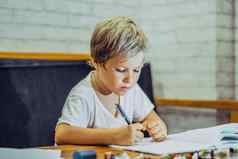 肖像金发碧眼的可爱的学前教育男孩持有笔笔记本硬努力努力学习写面部表达式手势孩子们行为教育问题首页学校概念
