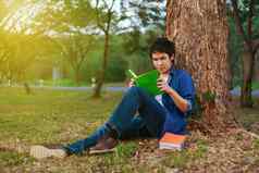 年轻的男人。坐着阅读书公园