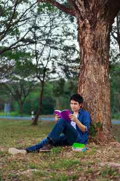 年轻的男人。坐着阅读书公园