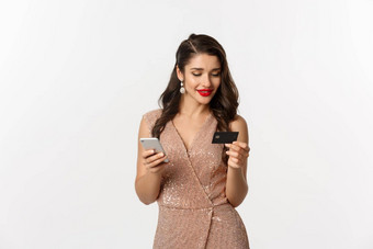 在线购物圣诞节概念优雅的年轻的女人支付互联网购买智能手机信贷卡站奢侈品衣服白色背景