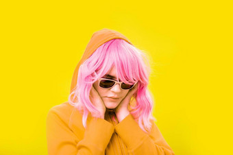 关闭时尚肖像年轻的美丽的女人连帽衫眼镜替代时髦的女孩粉红色的头发黄色的背景不寻常的青年时尚概念热图像