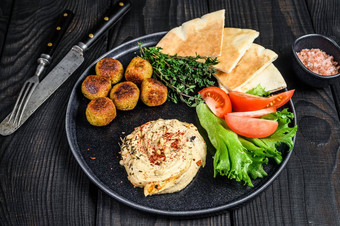 阿拉伯语厨房鹰嘴豆泥鹰嘴豆沙拉三明治丝带面包新鲜的蔬菜黑色的木背景前视图