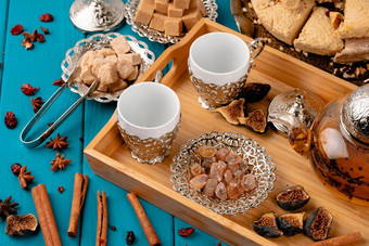 空杯木托盘糖多维数据集土耳其果仁蜜饼蓝色的木表格装饰肉桂棒