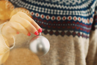 手女人节日毛衣持有圣诞节小玩意模糊灯
