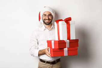 快乐圣诞节假期概念快乐年轻的男人。微笑持有礼物盒子穿圣诞老人他白色背景