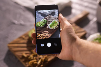 手图片智能手机美丽的健康的酸奶油鳄梨三明治说谎董事会表格社会媒体食物概念
