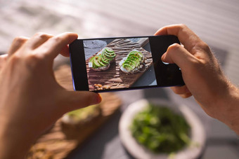 手图片智能手机美丽的健康的酸奶油鳄梨三明治说谎董事会表格社会媒体食物概念