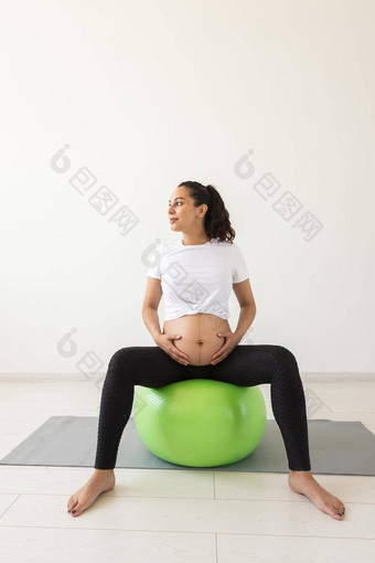 年轻的怀孕了女人放松锻炼健身球坐着席