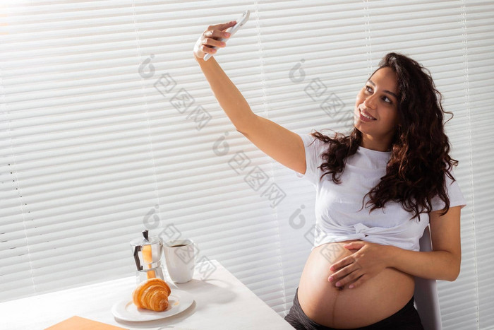 怀孕了女人采取肖像智能手机早餐