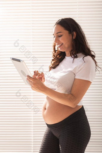 快乐怀孕了年轻的美丽的女人会说话的丈夫视频连接平板电脑概念沟通积极的的态度怀孕
