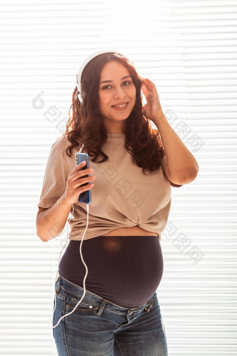 美丽的年轻的和平怀孕了女人听愉快的<strong>经典音乐</strong>智能手机耳机概念积极的的态度分娩