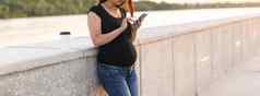 怀孕了女人智能手机公园怀孕技术沟通概念复制空间
