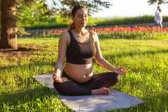 和平年轻的积极的怀孕了女人体操西装瑜伽冥想坐着席绿色草阳光明媚的温暖的夏天一天概念准备分娩积极的的态度