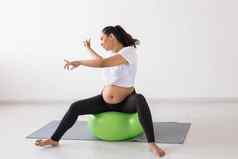 快乐的怀孕了女人舞蹈坐着健身球幸福怀孕健康的生活方式积极的概念
