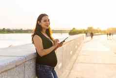 怀孕了女人智能手机在户外怀孕技术沟通概念