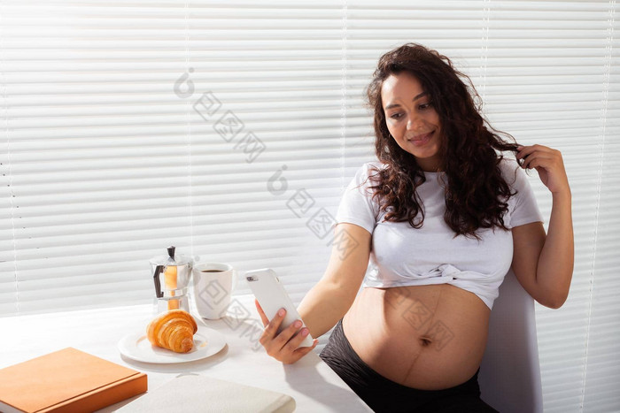 怀孕了女人采取肖像智能手机早餐