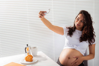 怀孕了女人需要自拍智能手机早餐孕妇离开技术概念