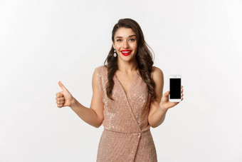 在线购物美丽的年轻的女人聚会，派对衣服化妆显示拇指移动屏幕赞扬好应用程序白色背景