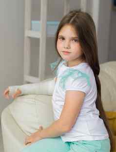 孩子投破碎的手腕手臂坐在沙发上复苏孩子概念