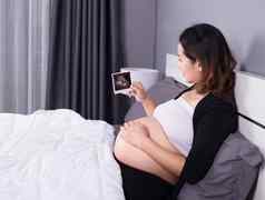 怀孕了女人超声波图像婴儿坐着床上卧室首页