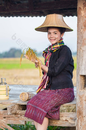 农民女人持有大米坐着小屋大米场