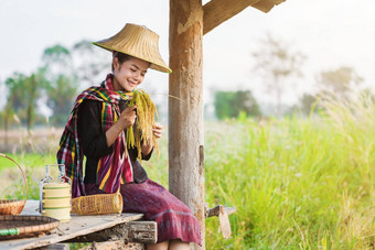 农民女人持有大米坐着小屋大米场