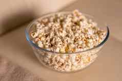 碗爆米花看电影米色沙发上零食不健康的垃圾食物概念