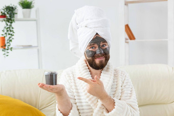 有胡子的男人。有趣的化妆品面具脸使黑色的粘土但皮肤护理幽默水疗中心首页概念
