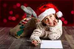 可爱的女孩穿圣诞老人他写作圣诞老人信