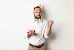 假期庆祝活动快乐的男人。享受生日吹聚会，派对吹口哨持有bday蛋糕白色背景