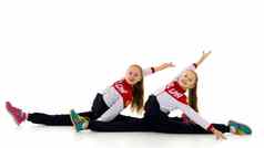 双胞胎姐妹运动服装坐着地板上水平线