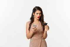 在线购物假期概念时尚的女人优雅的衣服困惑信贷卡支付移动电话白色背景