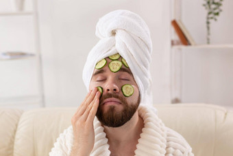有胡子的男人。享受化妆品面具脸使片黄瓜但皮肤护理水疗中心首页概念