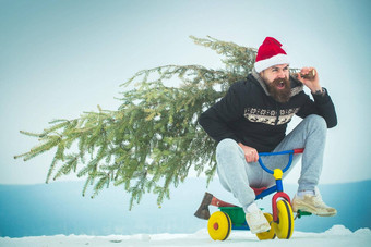 兴奋骑自行车的人圣诞老人他松圣诞节树孩子们自行车快乐赶时髦的人携带圣诞节树白色雪男人。骑三轮车雪景观