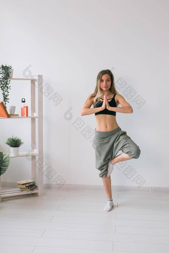 女人练习瑜伽执行树构成站席内部舒适的房间植物绿色植物健康的生活方式概念
