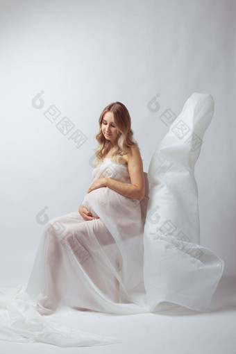 优雅的怀孕了年轻的女人站穿飞行白色织物怀孕<strong>孕妇母亲</strong>概念