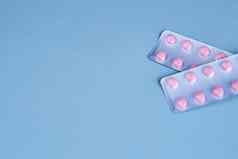 粉红色的药片包维生素疼痛减压装置蓝色的背景