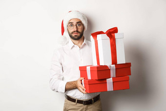 快乐圣诞节假期概念困惑男人。圣诞老人他持有桩礼物发现礼物圣诞节树站白色背景