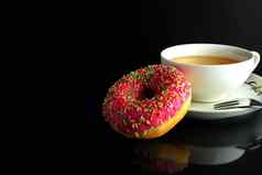 甜甜圈粉红色的糖衣柏林谎言杯咖啡茶美味的早餐零食一天饮食黑色的背景Copyspace