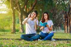 年轻的夫妇阅读书听音乐耳机公园