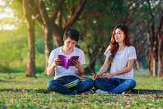年轻的夫妇阅读书听音乐耳机公园