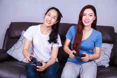 年轻的女人操纵杆控制器玩视频游戏沙发首页