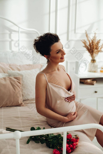 有吸引力的怀孕了女人摆姿势相机床上