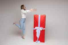 快乐的女模型提出了相机大红色的盒子圣诞节现在喜乐很多