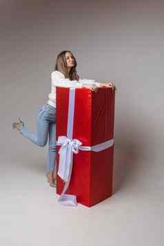 美丽的女模型提出了相机大红色的盒子圣诞节现在